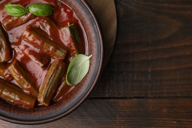 Tasty stew with okra, tomato sauce and basil on wooden table, top view. Space for text