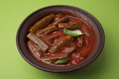 Photo of Tasty stew with okra, tomato sauce and basil on light green background, closeup