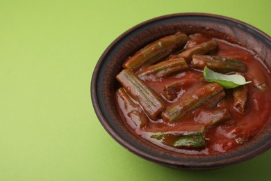 Photo of Tasty stew with okra, tomato sauce and basil on light green background, closeup. Space for text