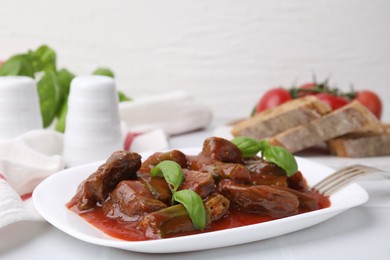 Photo of Tasty stew with okra, tomato sauce, bread and basil on white tiled table, closeup