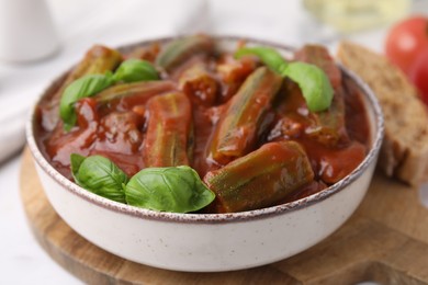 Tasty stew with okra, tomato sauce and basil on table, closeup