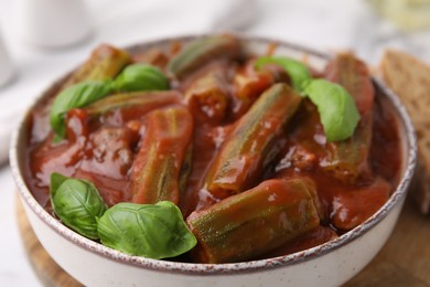 Photo of Tasty stew with okra, tomato sauce and basil on table, closeup