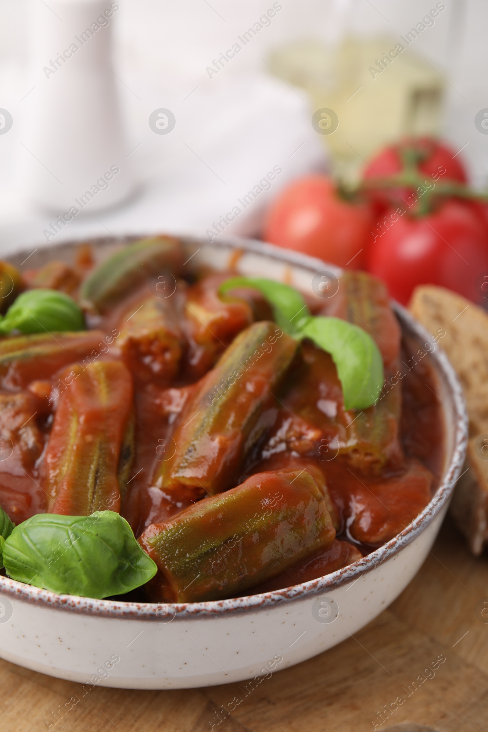 Photo of Tasty stew with okra, tomato sauce and basil on table, closeup