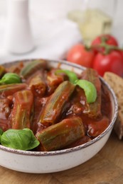 Photo of Tasty stew with okra, tomato sauce and basil on table, closeup