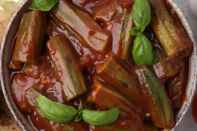 Tasty stew with okra, tomato sauce and basil on table, top view