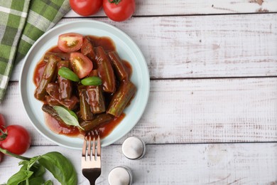 Photo of Tasty stew with okra, tomato sauce and basil on white wooden table, flat lay. Space for text