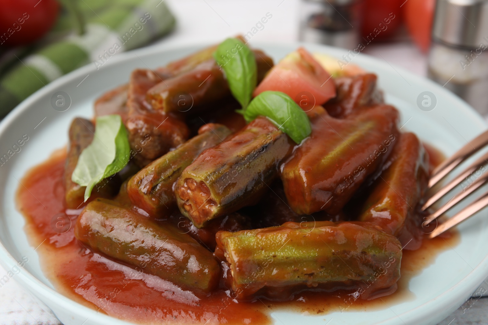 Photo of Tasty stew with okra, tomato sauce and basil on table, closeup