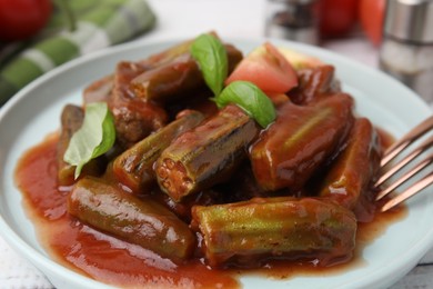 Tasty stew with okra, tomato sauce and basil on table, closeup