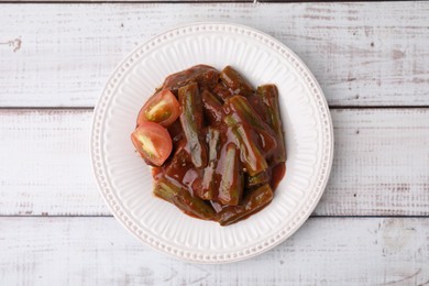 Tasty stew with okra and tomato sauce on white wooden table, top view