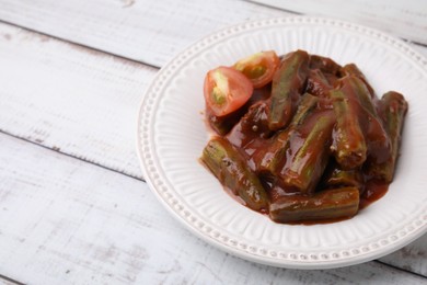 Tasty stew with okra and tomato sauce on white wooden table, space for text