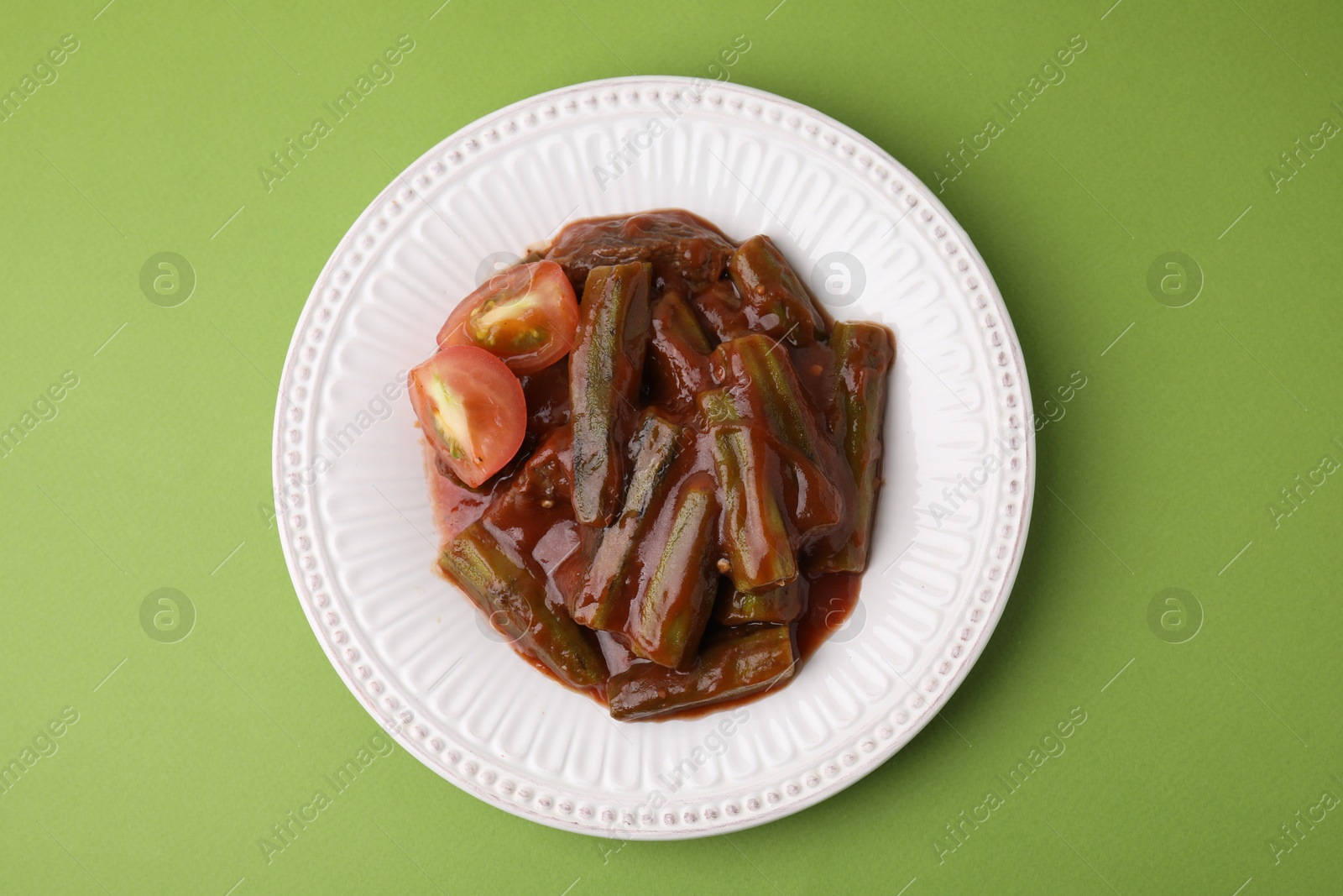 Photo of Tasty stew with okra and tomato sauce on light green background, top view