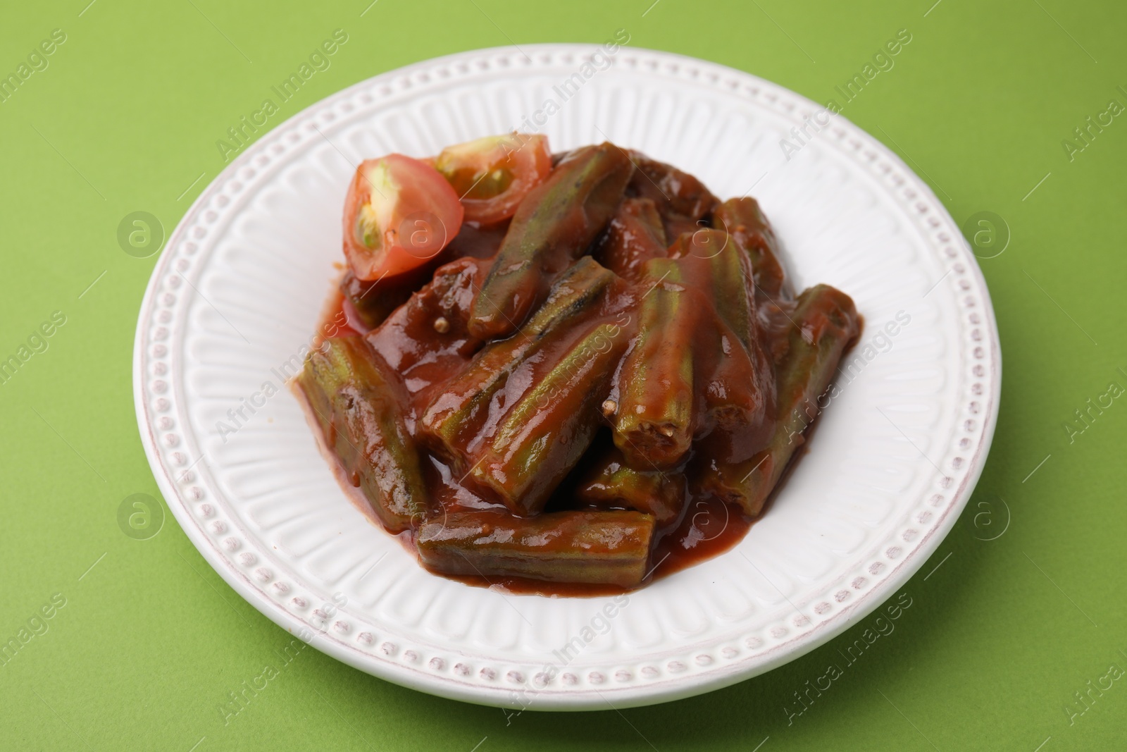 Photo of Tasty stew with okra and tomato sauce on light green background, closeup