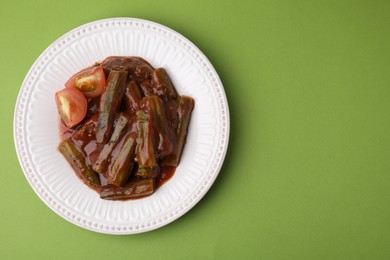 Tasty stew with okra and tomato sauce on light green background, top view. Space for text