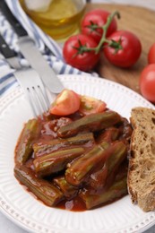 Photo of Tasty stew with okra, tomato sauce and bread on white table, closeup