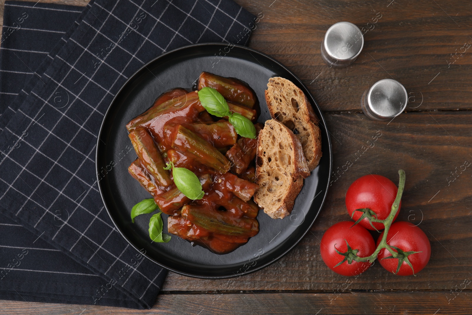 Photo of Tasty stew with okra, tomato sauce, bread and basil on wooden table, flat lay