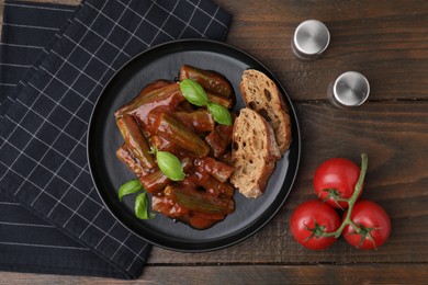 Photo of Tasty stew with okra, tomato sauce, bread and basil on wooden table, flat lay