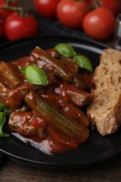 Photo of Tasty stew with okra, tomato sauce, bread and basil on wooden table, closeup