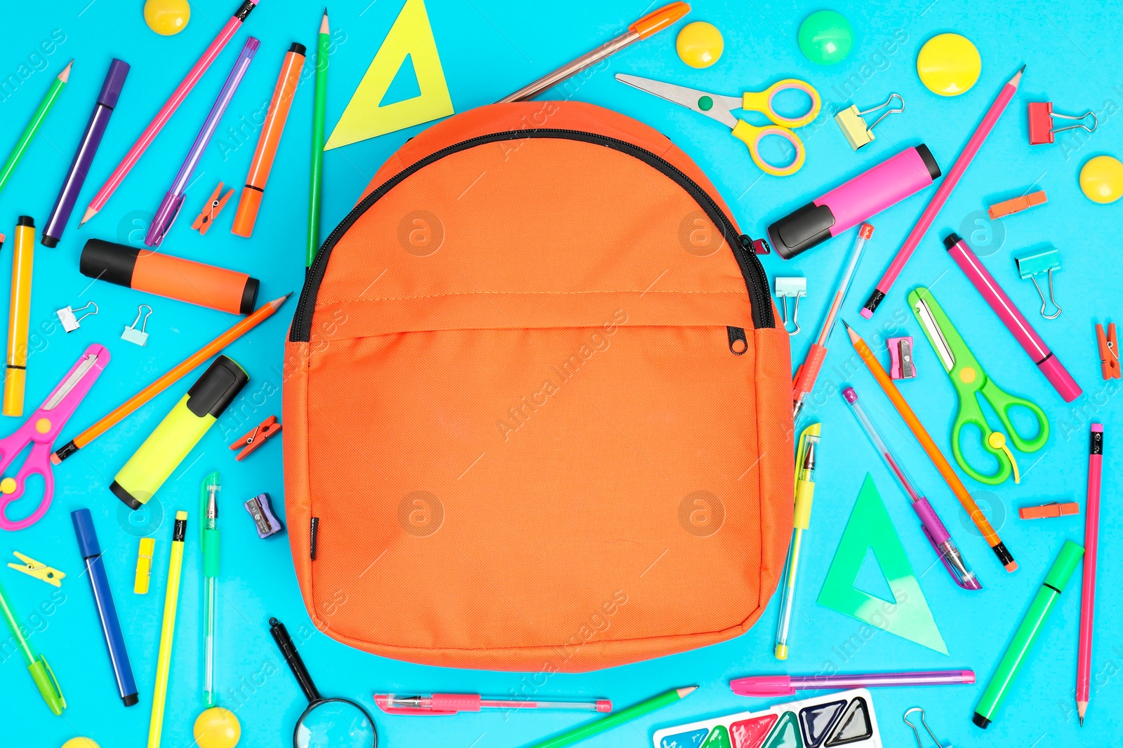 Photo of Backpack and different school supplies on light blue background, flat lay