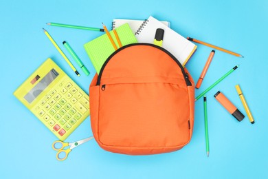 Backpack and different school supplies on light blue background, flat lay