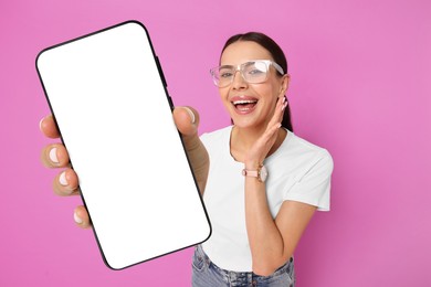 Image of Happy woman showing mobile phone with blank screen on magenta background. Mockup for design