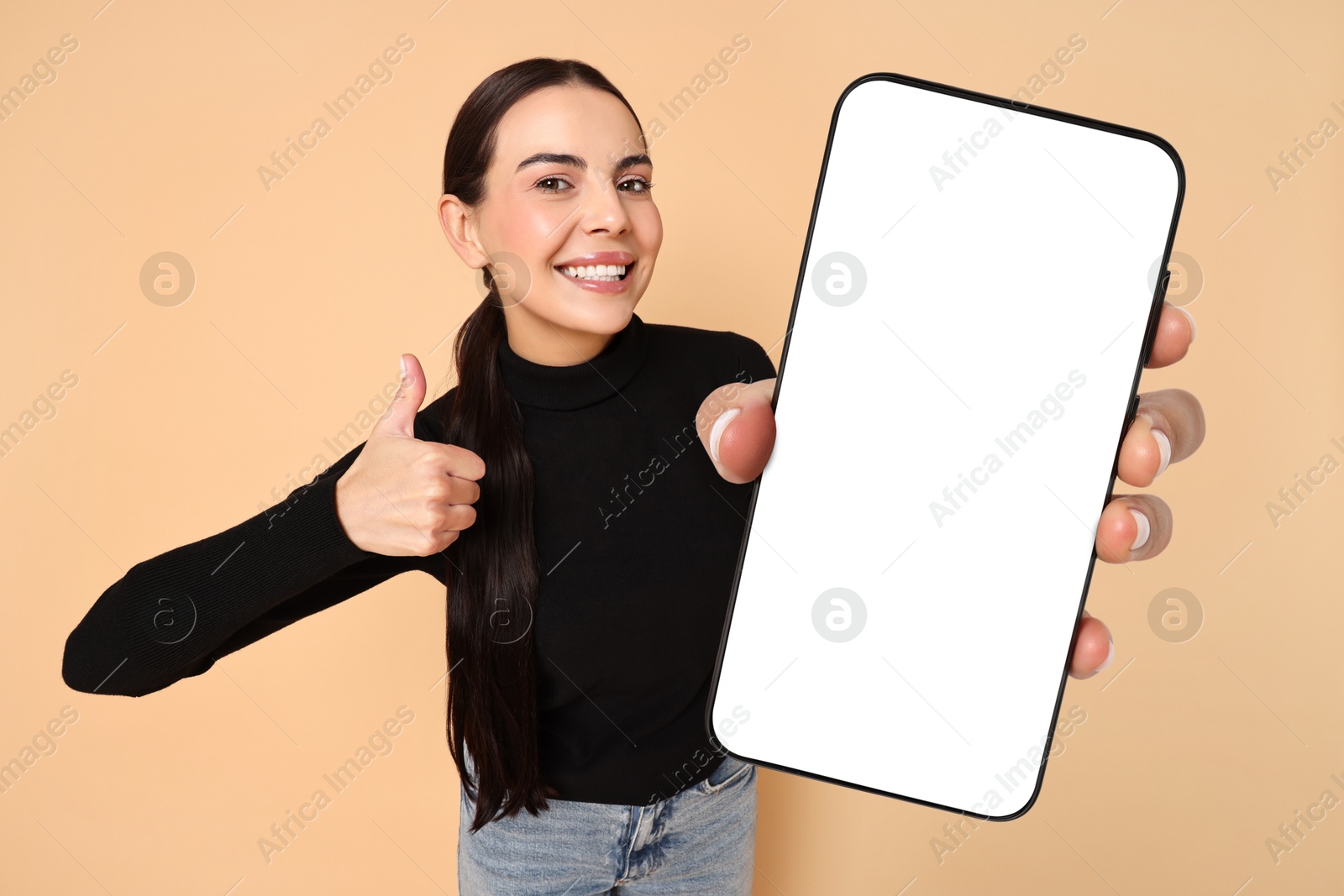 Image of Happy woman showing mobile phone with blank screen on dark beige background. Mockup for design