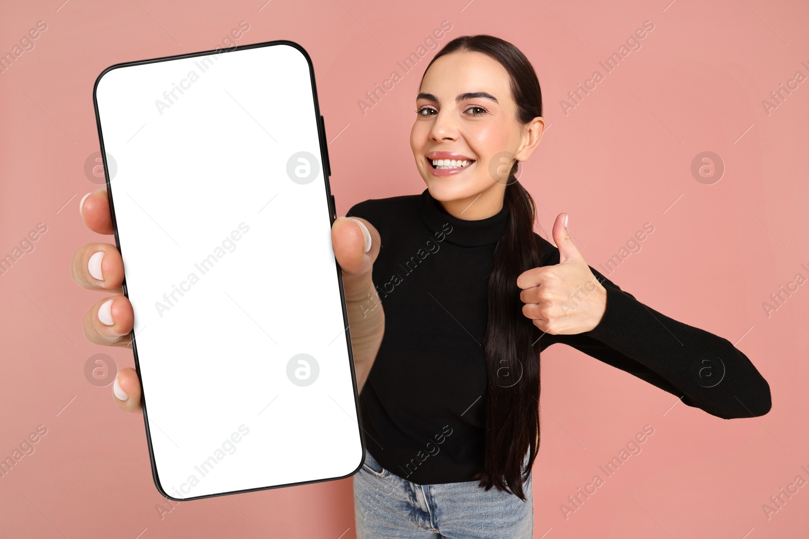 Image of Happy woman showing mobile phone with blank screen on beige pink background. Mockup for design