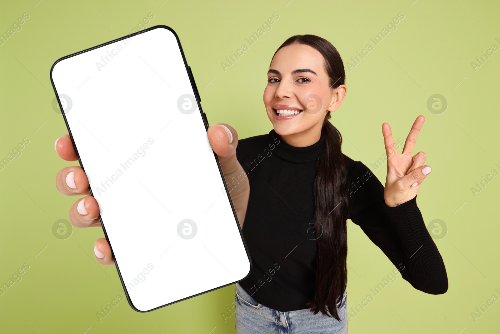 Image of Happy woman showing mobile phone with blank screen on light green background. Mockup for design