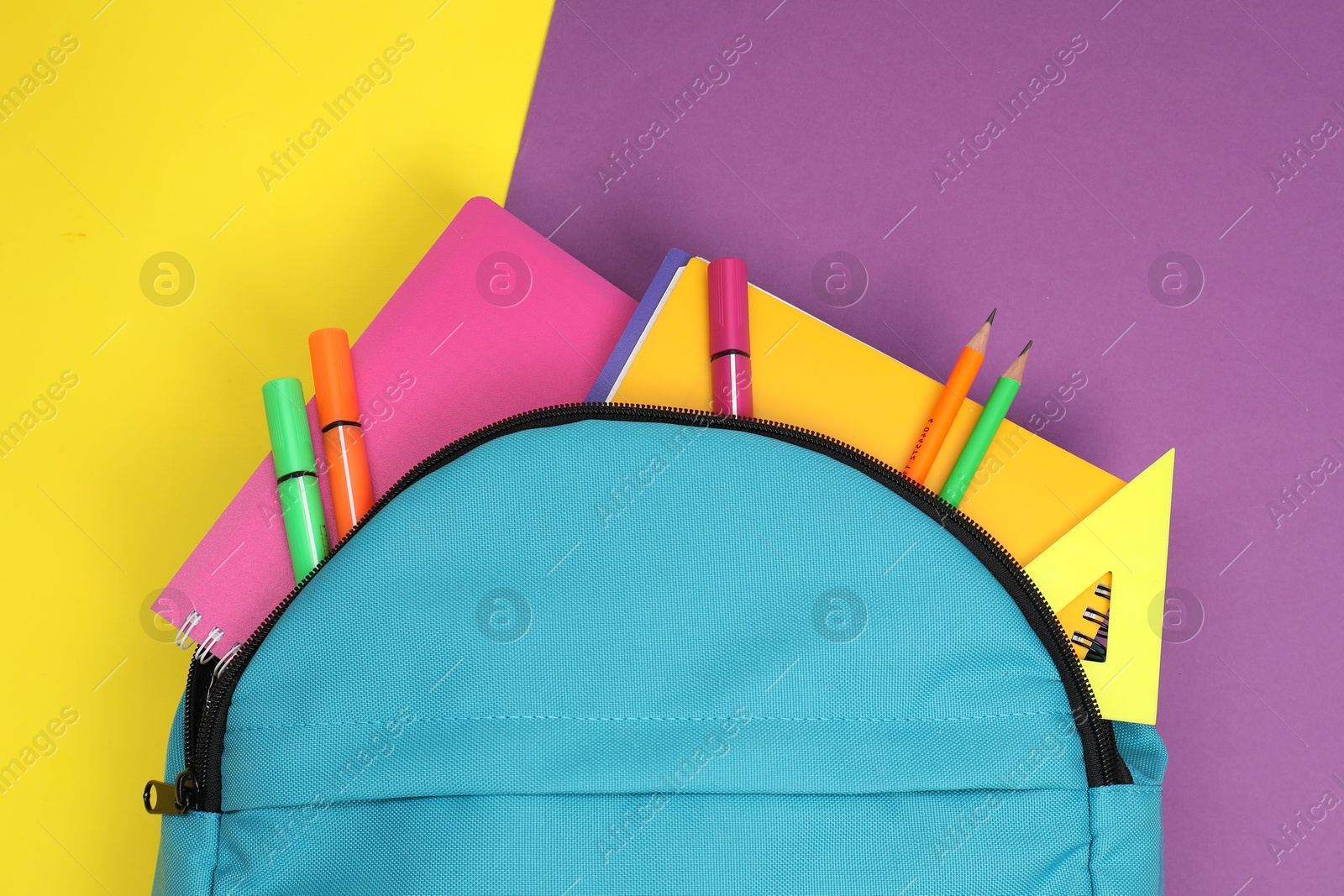 Photo of Backpack and different school stationery on color background, top view