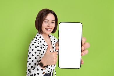 Image of Happy woman showing mobile phone with blank screen on green background. Mockup for design