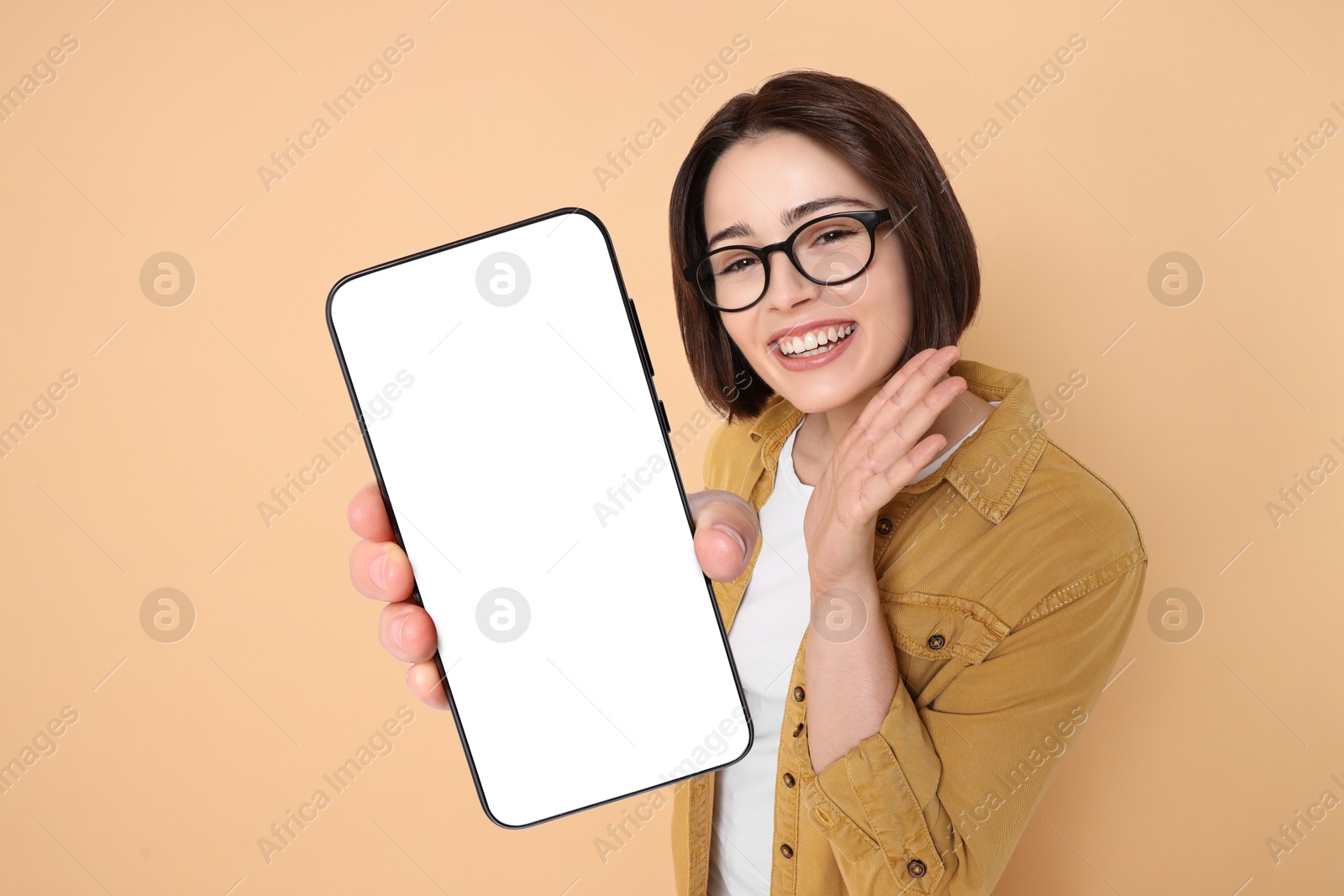 Image of Happy woman showing mobile phone with blank screen on dark beige background. Mockup for design