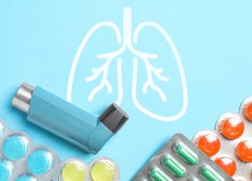 Image of Asthma inhaler, drugs and illustration of lungs on light blue background, flat lay