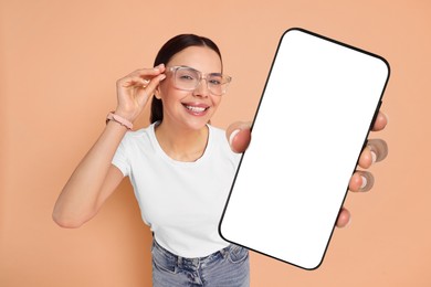 Image of Happy woman showing mobile phone with blank screen on dark beige background. Mockup for design