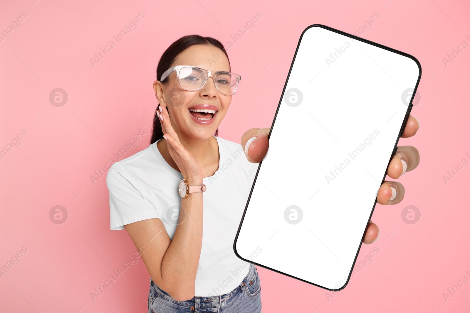 Image of Happy woman showing mobile phone with blank screen on pink background. Mockup for design