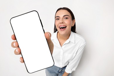 Happy woman showing mobile phone with blank screen on white background. Mockup for design