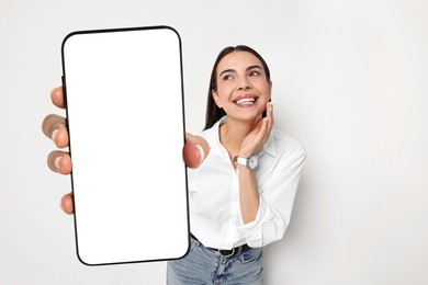 Image of Happy woman showing mobile phone with blank screen on white background. Mockup for design