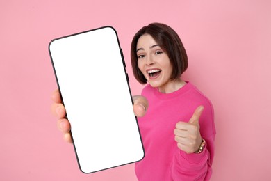 Image of Happy woman showing mobile phone with blank screen on pink background. Mockup for design