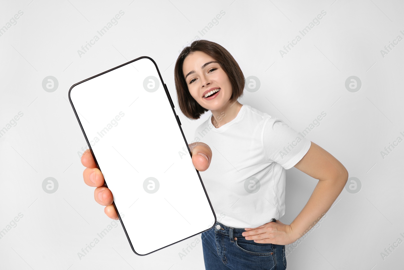 Image of Happy woman showing mobile phone with blank screen on white background. Mockup for design