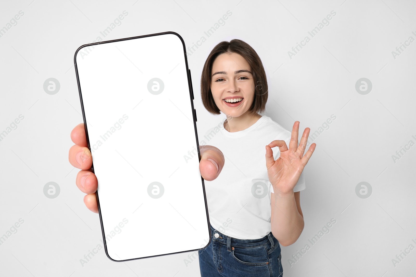 Image of Happy woman showing mobile phone with blank screen on white background. Mockup for design