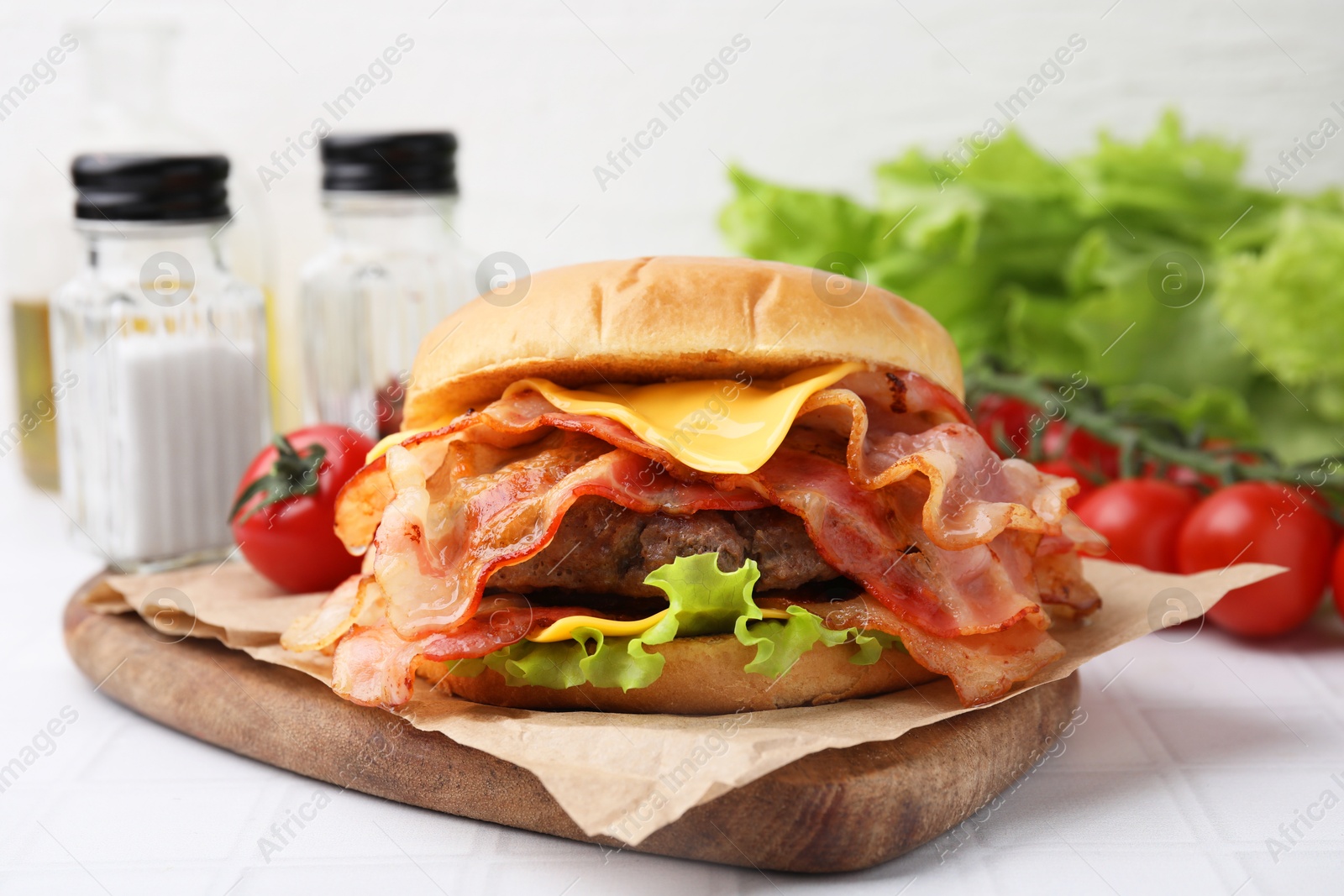 Photo of Delicious burger with bacon, patty and cheese on white tiled table