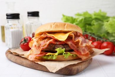 Photo of Delicious burger with bacon, patty and cheese on white tiled table