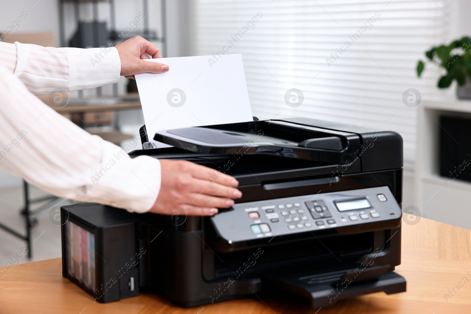 Photo of Woman using modern printer at workplace indoors, closeup