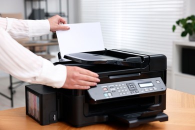 Photo of Woman using modern printer at workplace indoors, closeup