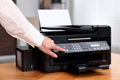 Photo of Woman using modern printer at workplace indoors, closeup