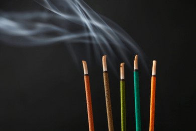 Photo of Aromatic incense sticks smoldering on black background