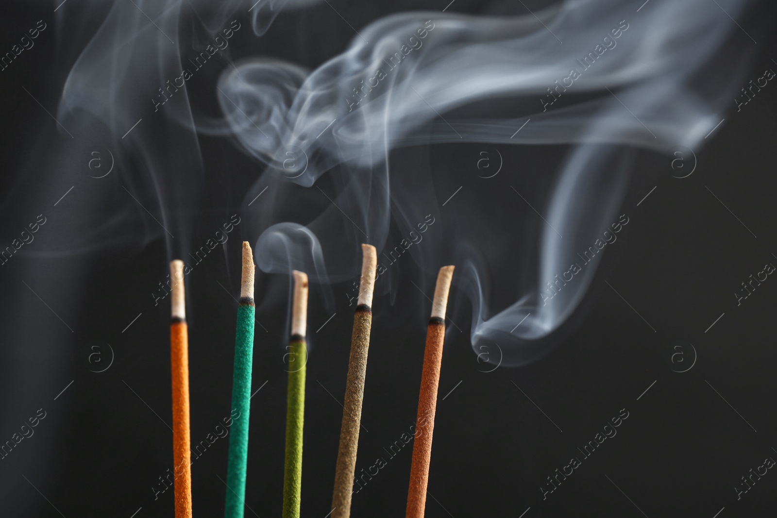 Photo of Aromatic incense sticks smoldering on black background