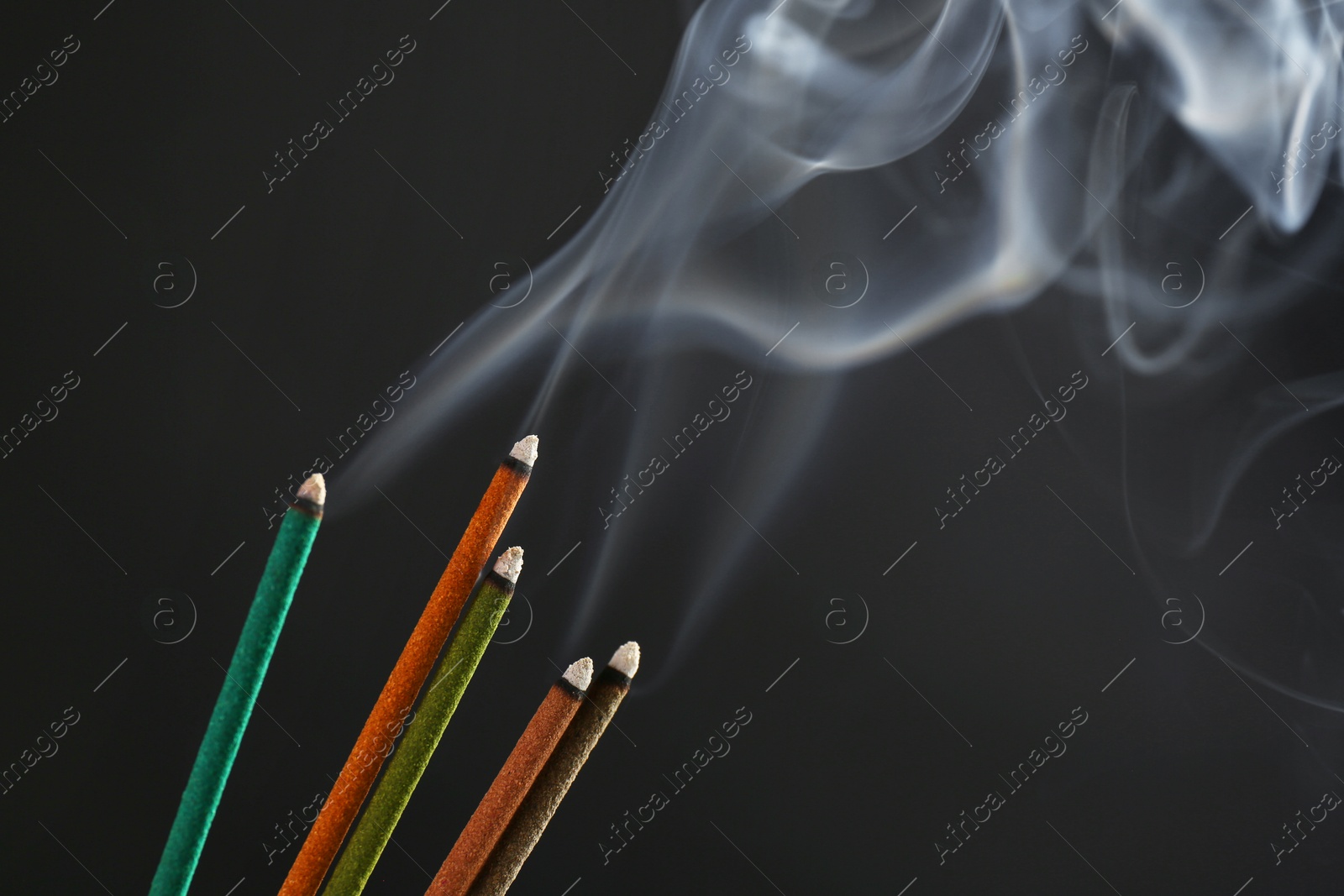 Photo of Aromatic incense sticks smoldering on black background