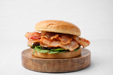 Photo of Delicious burger with bacon and greens on white table, closeup