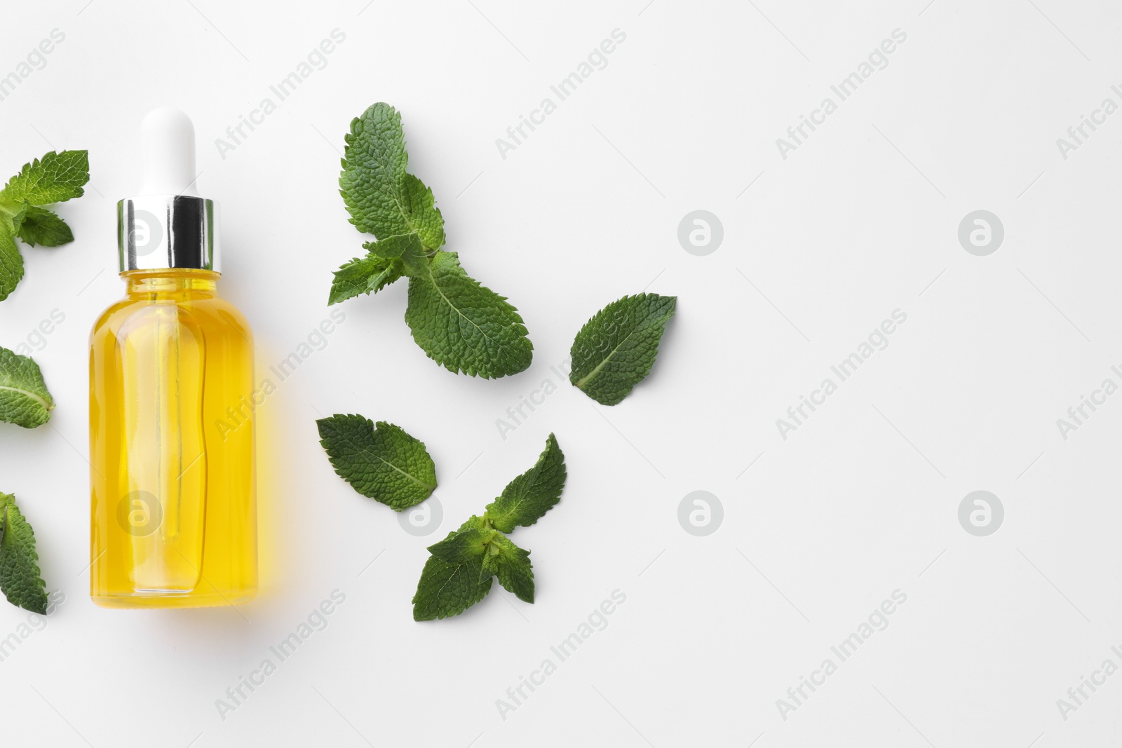 Photo of Bottle of essential oil and mint isolated on white, top view