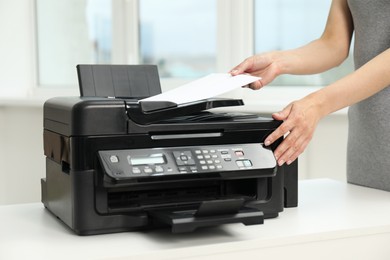 Photo of Woman using modern printer at workplace indoors, closeup