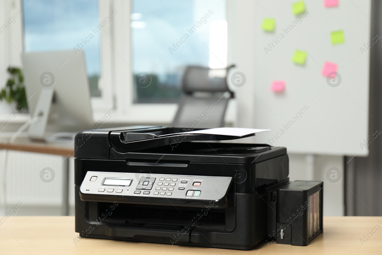 Photo of Modern printer with paper on wooden table in office